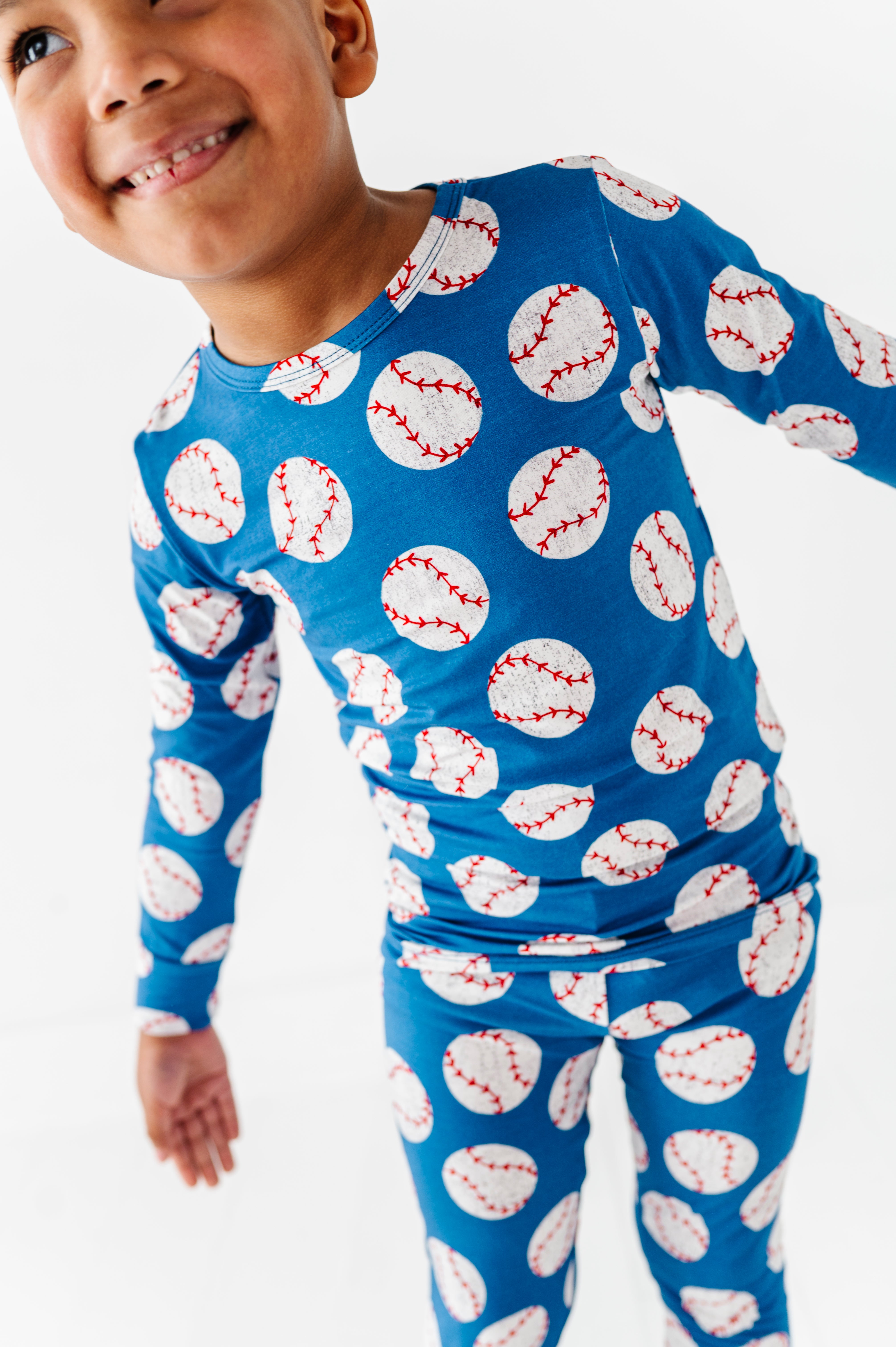 Child wearing a blue bamboo pajama set with baseball pattern on a white background